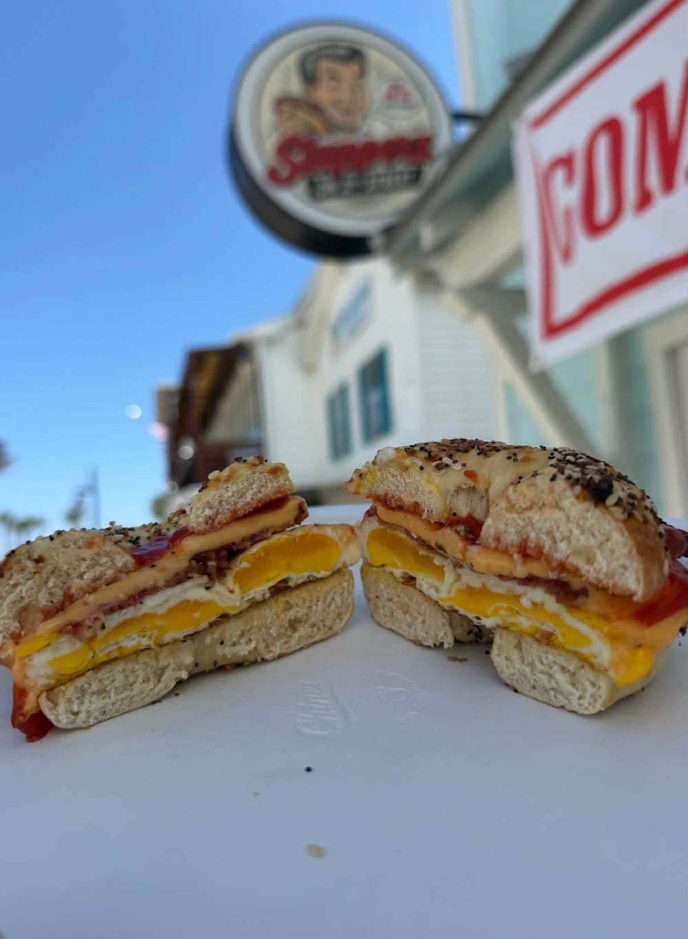 A bacon, egg and cheese on an everything bagel, cut in half to show the runny egg yolk and melted cheese